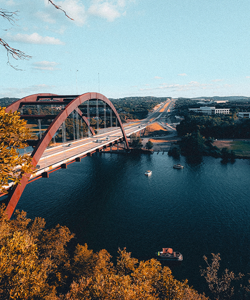 Pennybacker Bridge spanning Lake Austin, with boats on the water and tree-covered hills beyond