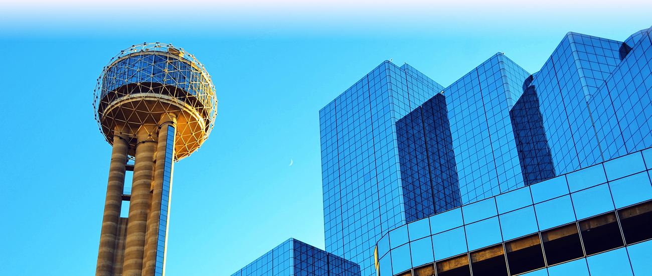 Reunion Tower beside reflective glass skyscrapers against a bright blue Dallas sky.